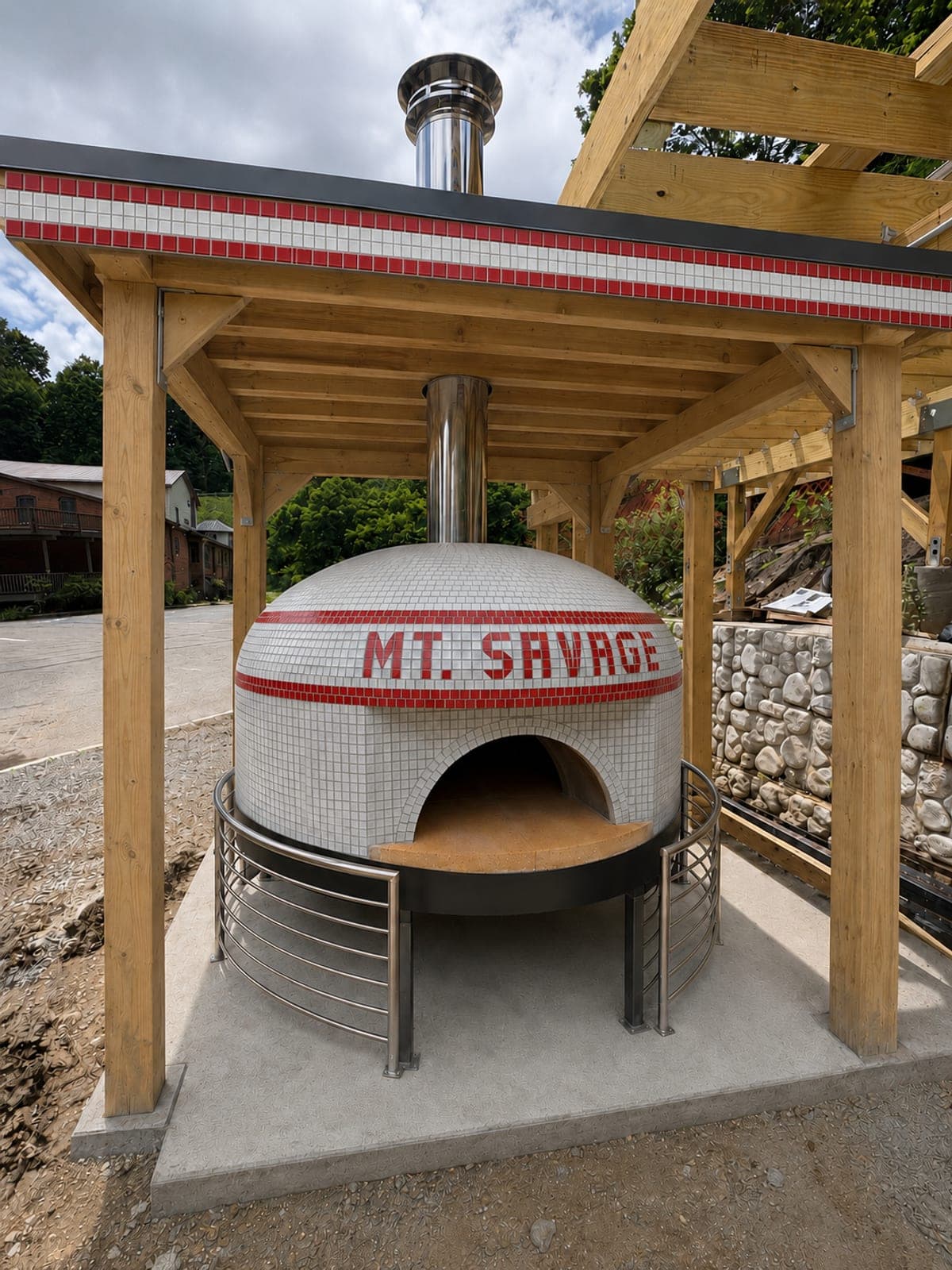 The Mt. Savage brick pizza oven — a white-tiled dome with a red mosaic band — under its timber pavilion beside the GAP trailhead